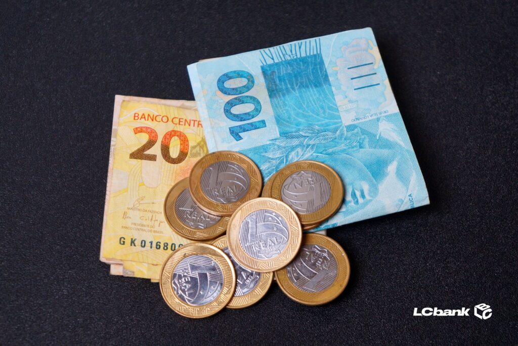 Notas de 20 e 100 reais e moedas de 1 real sobre fundo escuro, representando dívidas judiciais da União e o pagamento de precatórios — valores reconhecidos pelo governo após decisões definitivas.